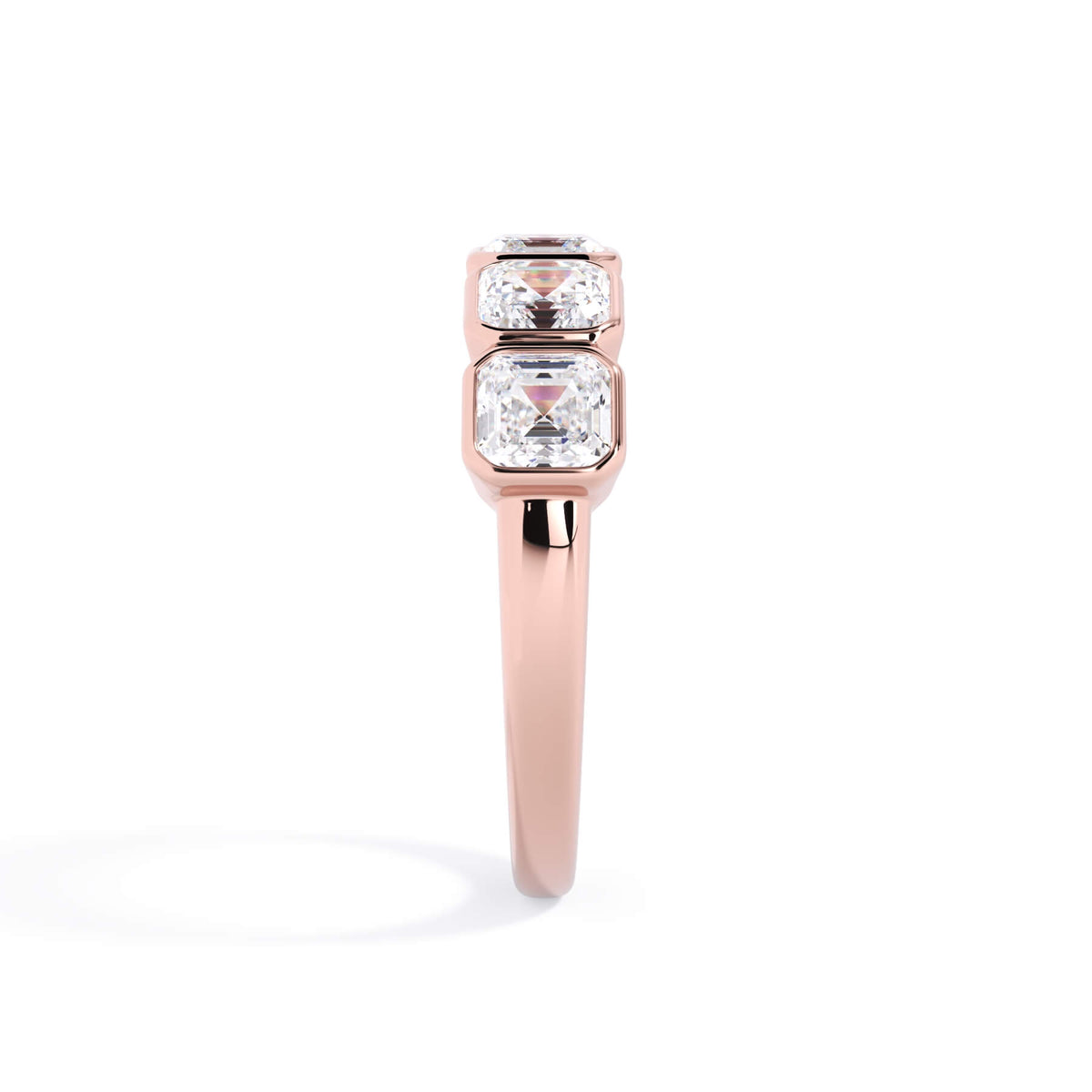 A picture of a five stone diamond wedding ring with asscher shape diamonds that are bezel set in rose gold on a white background with a side profile view.