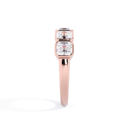 A picture of a five stone diamond wedding ring with asscher shape diamonds that are bezel set in rose gold on a white background with a side profile view.