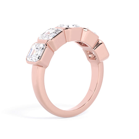 A picture of a five stone diamond wedding ring with asscher shape diamonds that are bezel set in rose gold on a white background with a slightly angled, through the finger view.