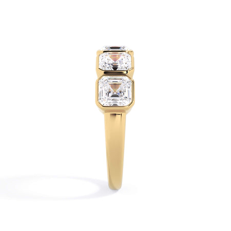 A picture of a five stone diamond wedding ring with asscher shape diamonds that are bezel set in yellow gold on a white background with a side profile view.