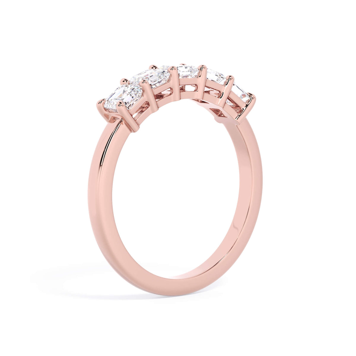 A picture of a five stone diamond wedding ring with asscher shape diamonds that are shared prong set in rose gold on a white background with a slightly angled, through the finger view.