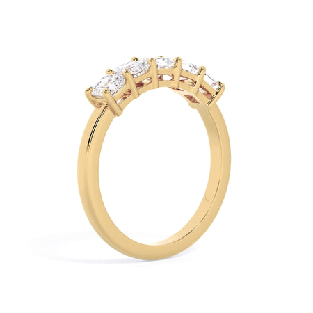 A picture of a five stone diamond wedding ring with asscher shape diamonds that are shared prong set in yellow gold on a white background with a slightly angled, through the finger view.