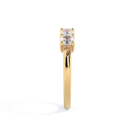 A picture of a five stone diamond wedding ring with asscher shape diamonds that are shared prong set in yellow gold on a white background with a side profile view.