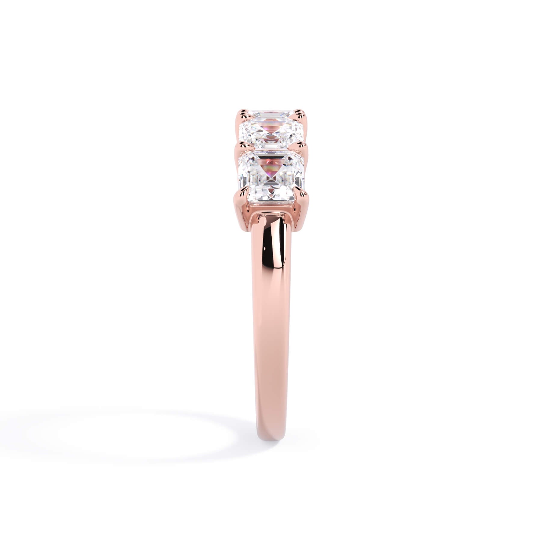 A picture of a five stone diamond wedding ring with asscher shape diamonds that are shared prong set in rose gold on a white background with a side profile view.