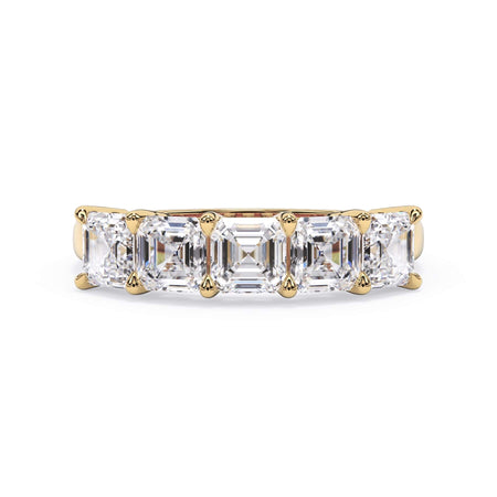 A picture of a five stone diamond wedding ring with asscher shape diamonds that are shared prong set in yellow gold on a white background with the ring facing forward, lying down.