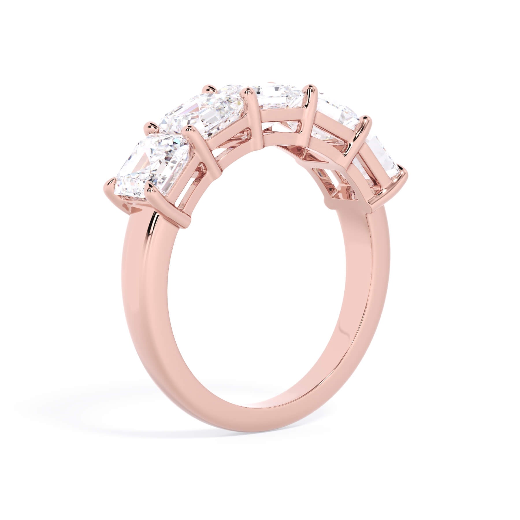 A picture of a five stone diamond wedding ring with asscher shape diamonds that are shared prong set in rose gold on a white background with a slightly angled, through the finger view.