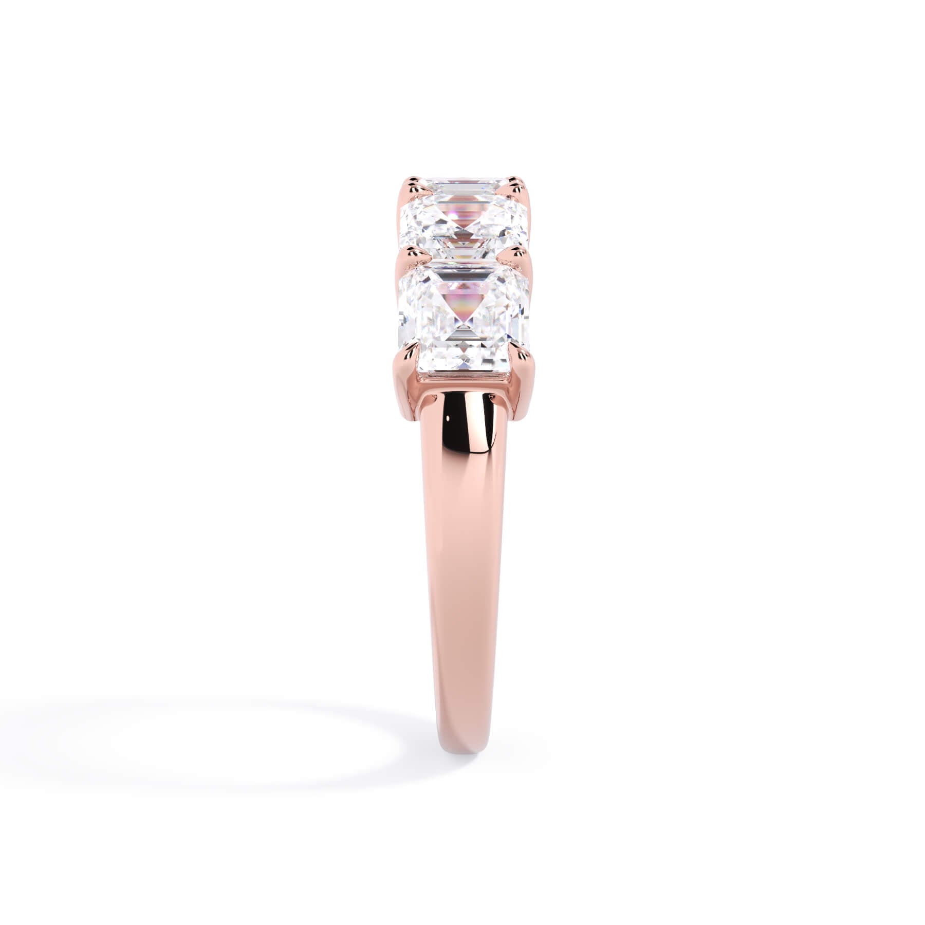 A picture of a five stone diamond wedding ring with asscher shape diamonds that are shared prong set in rose gold on a white background with a side profile view.