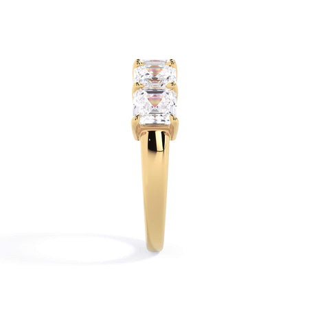 A picture of a five stone diamond wedding ring with asscher shape diamonds that are shared prong set in yellow gold on a white background with a side profile view.