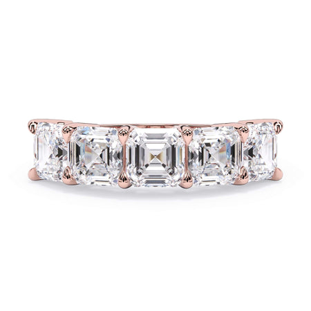 A picture of a five stone diamond wedding ring with asscher shape diamonds that are shared prong set in rose gold on a white background with the ring facing forward, lying down.