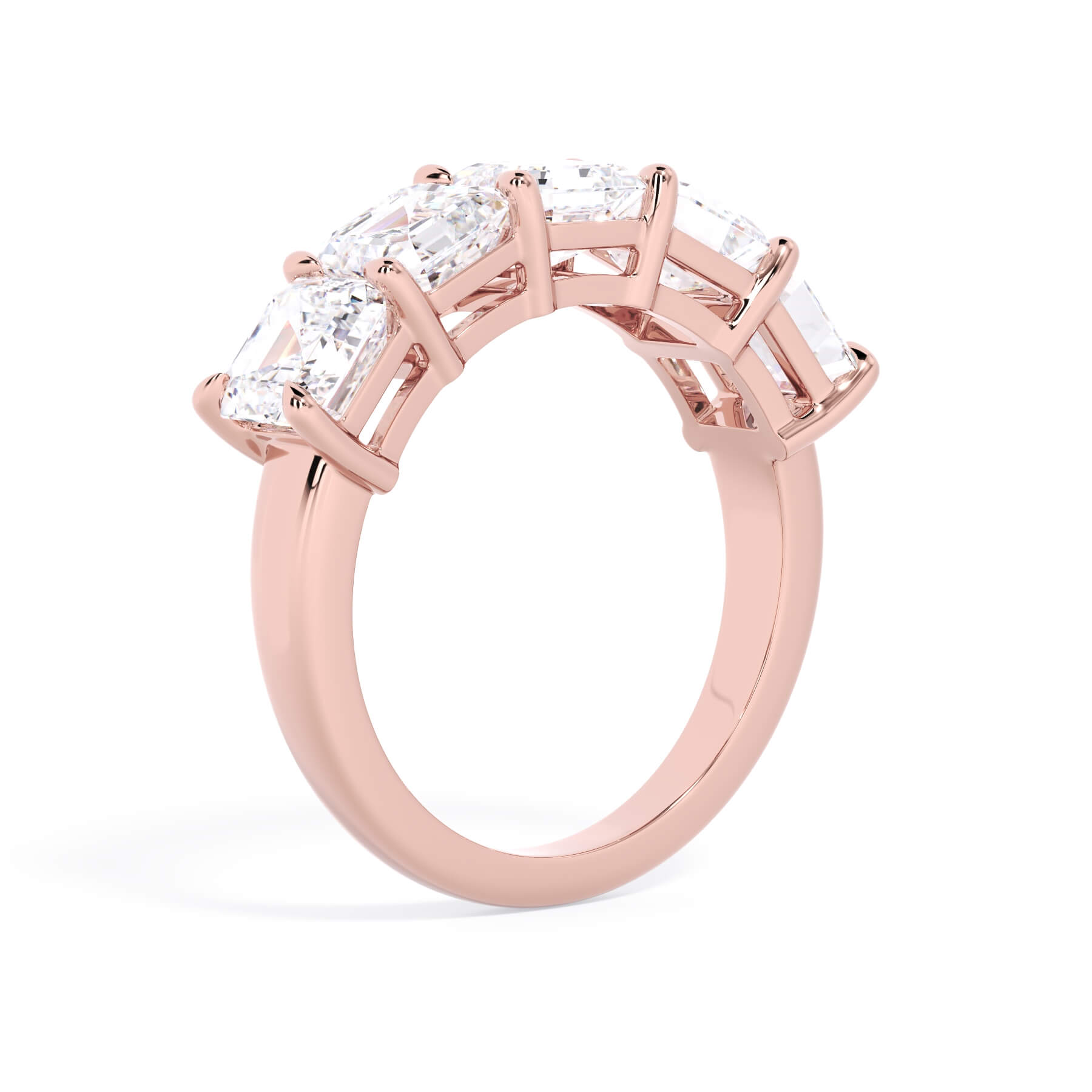 A picture of a five stone diamond wedding ring with asscher shape diamonds that are shared prong set in rose gold on a white background with a slightly angled, through the finger view.
