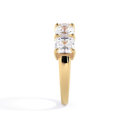 A picture of a five stone diamond wedding ring with asscher shape diamonds that are shared prong set in yellow gold on a white background with a side profile view.