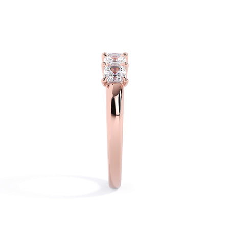 A picture of a five stone diamond wedding ring with asscher shape diamonds that are u prong set in rose gold on a white background with a side profile view.