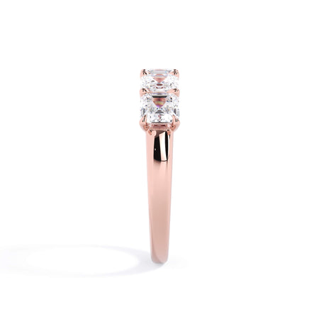 A picture of a five stone diamond wedding ring with asscher shape diamonds that are u prong set in rose gold on a white background with a side profile view.