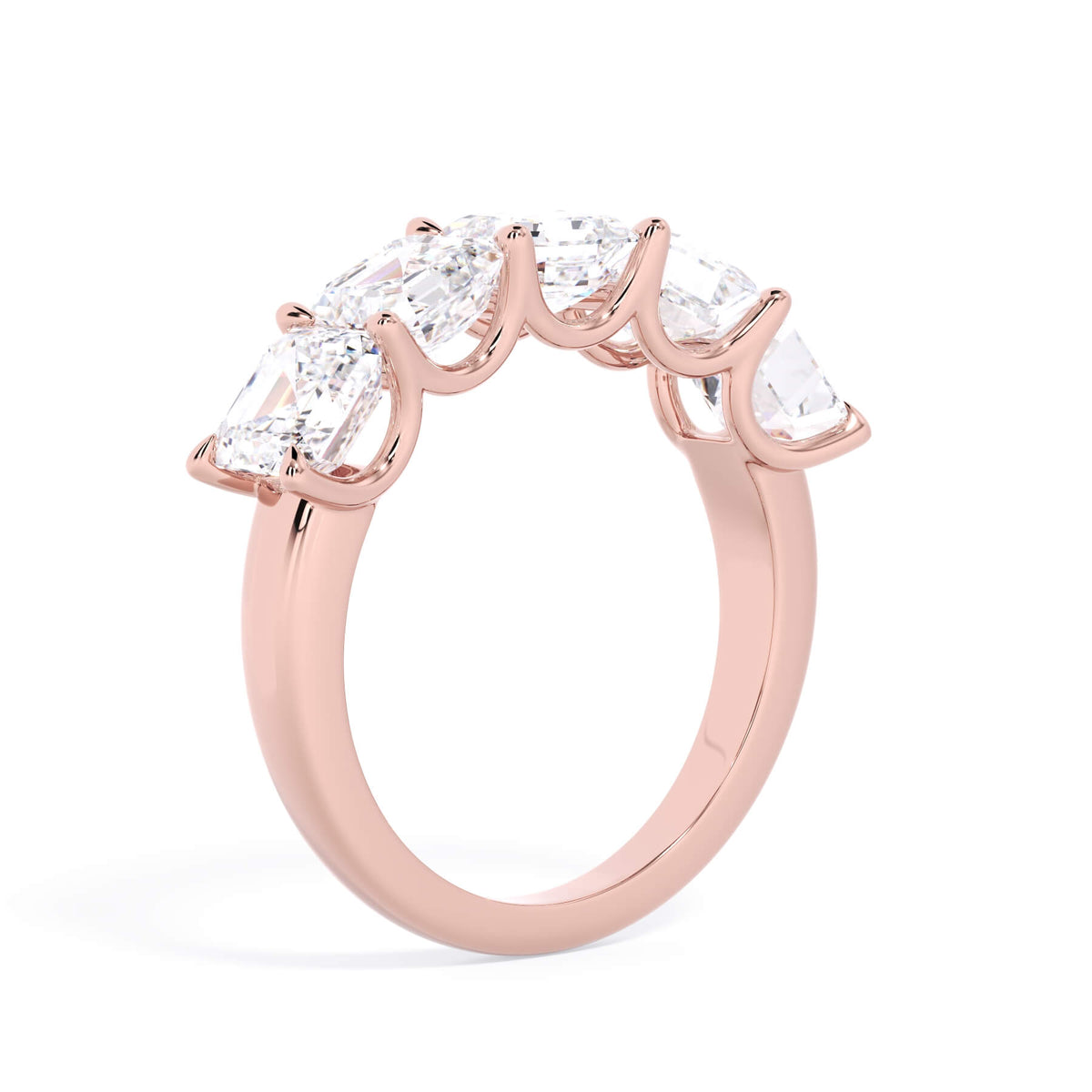 A picture of a five stone diamond wedding ring with asscher shape diamonds that are u prong set in rose gold on a white background with a slightly angled, through the finger view.