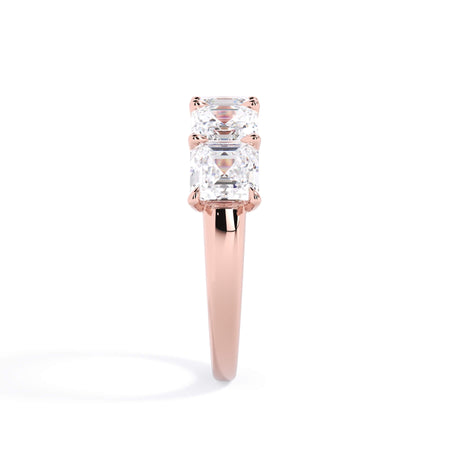 A picture of a five stone diamond wedding ring with asscher shape diamonds that are u prong set in rose gold on a white background with a side profile view.