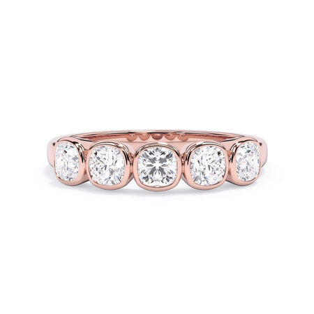 A picture of a five stone diamond wedding ring with cushion shape diamonds that are bezel set in rose gold on a white background with the ring facing forward, lying down.