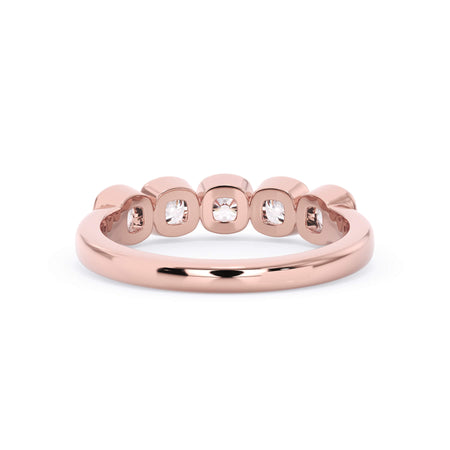 A picture of a five stone diamond wedding ring with cushion shape diamonds that are bezel set in rose gold on a white background with a view of the underside of the ring.