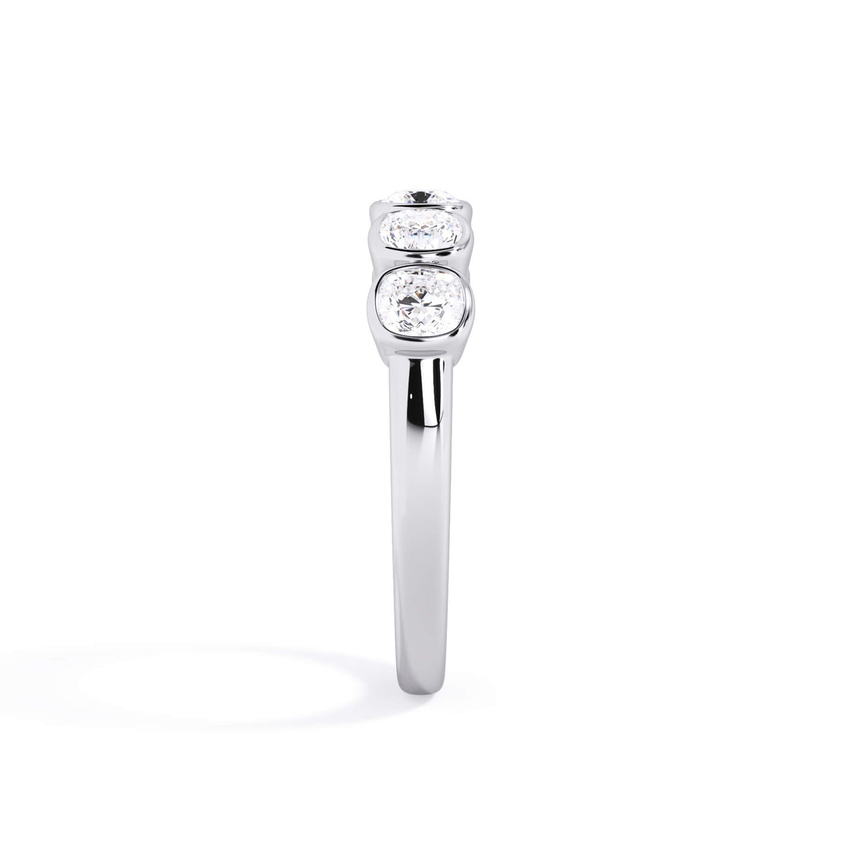 A picture of a five stone diamond wedding ring with cushion shape diamonds that are bezel set in white gold or platinum on a white background with a side profile view.