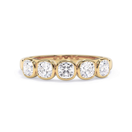 A picture of a five stone diamond wedding ring with cushion shape diamonds that are bezel set in yellow gold on a white background with the ring facing forward, lying down.