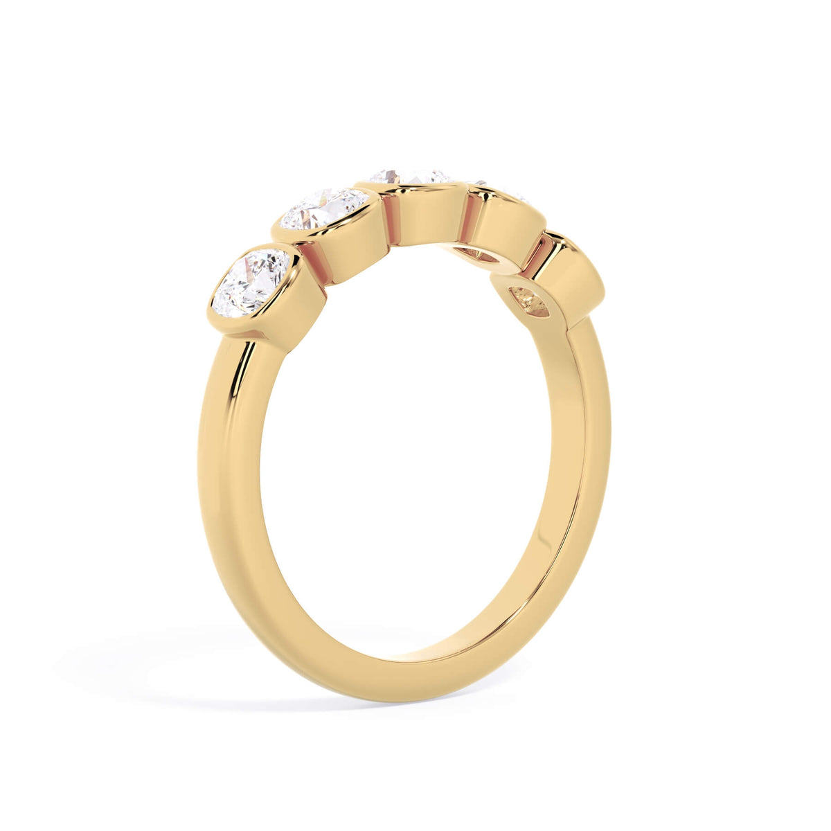 A picture of a five stone diamond wedding ring with cushion shape diamonds that are bezel set in yellow gold on a white background with a slightly angled, through the finger view.