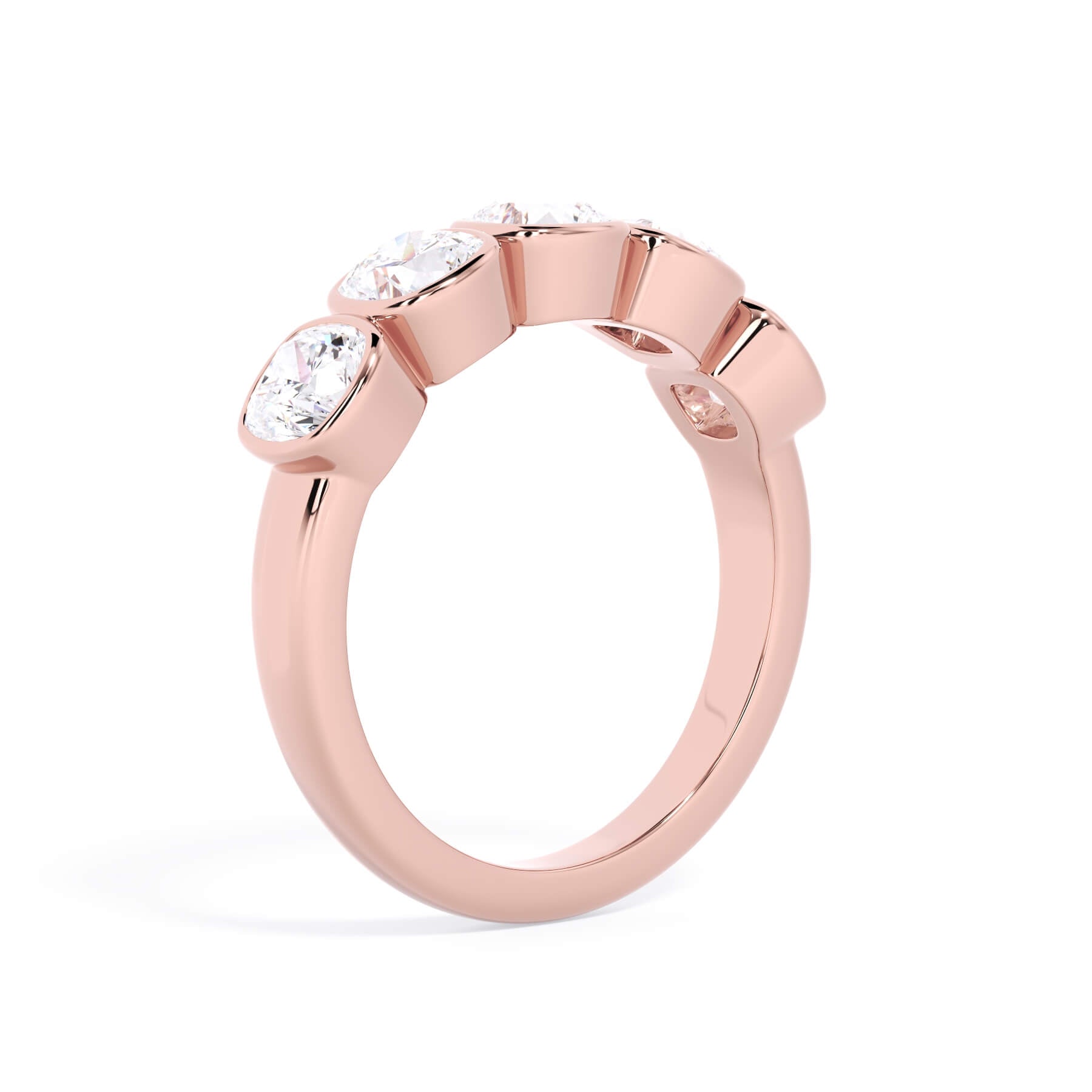 A picture of a five stone diamond wedding ring with cushion shape diamonds that are bezel set in rose gold on a white background with a slightly angled, through the finger view.
