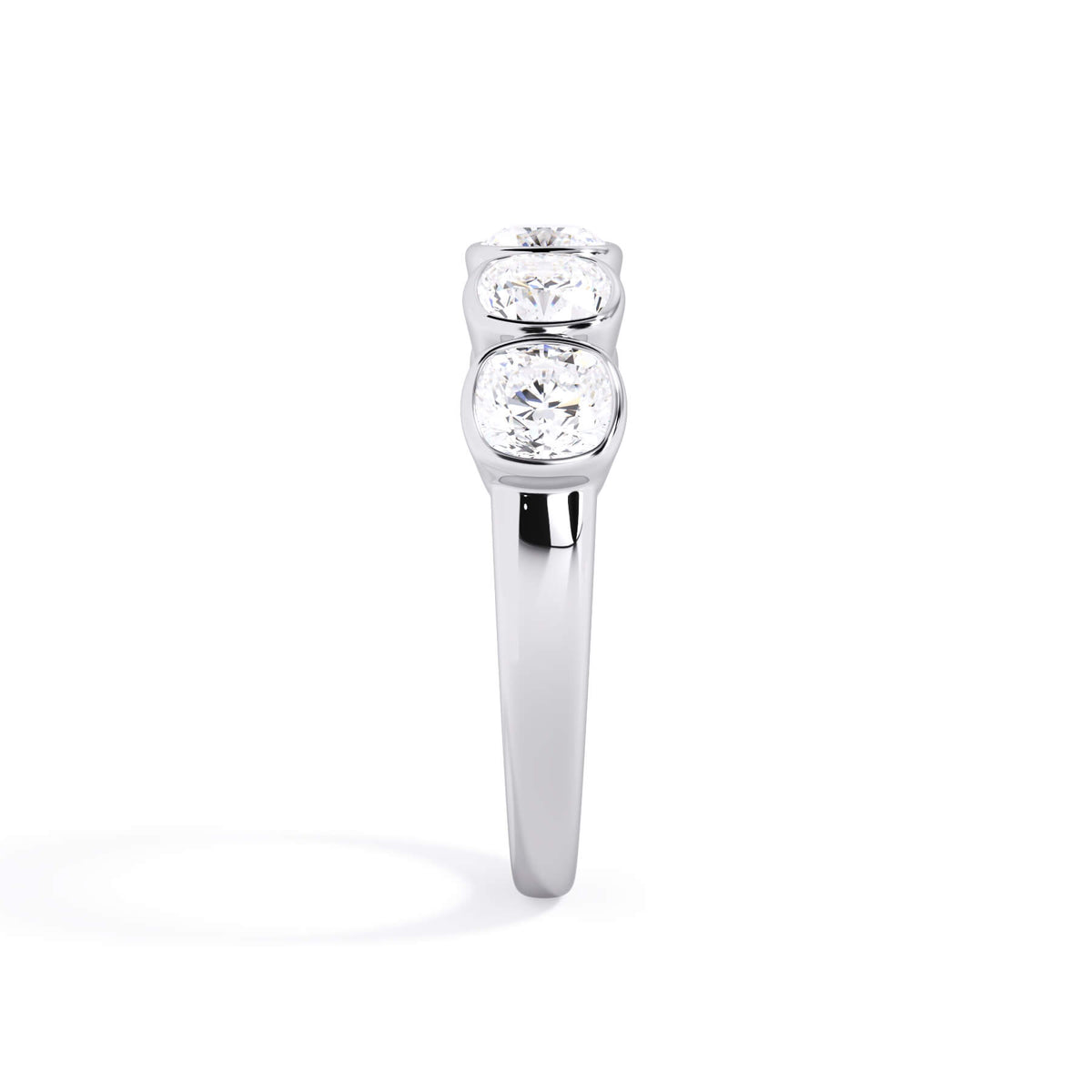 A picture of a five stone diamond wedding ring with cushion shape diamonds that are bezel set in white gold or platinum on a white background with a side profile view.