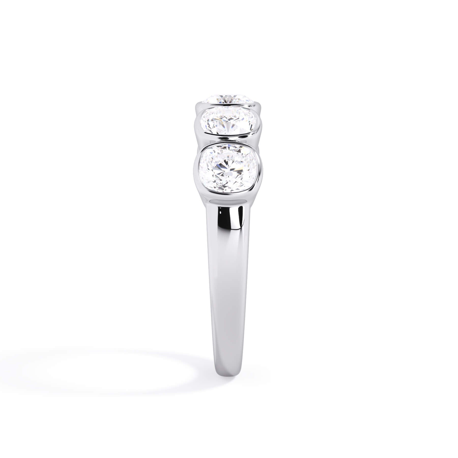 A picture of a five stone diamond wedding ring with cushion shape diamonds that are bezel set in white gold or platinum on a white background with a side profile view.