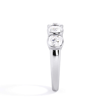 A picture of a five stone diamond wedding ring with cushion shape diamonds that are bezel set in white gold or platinum on a white background with a side profile view.