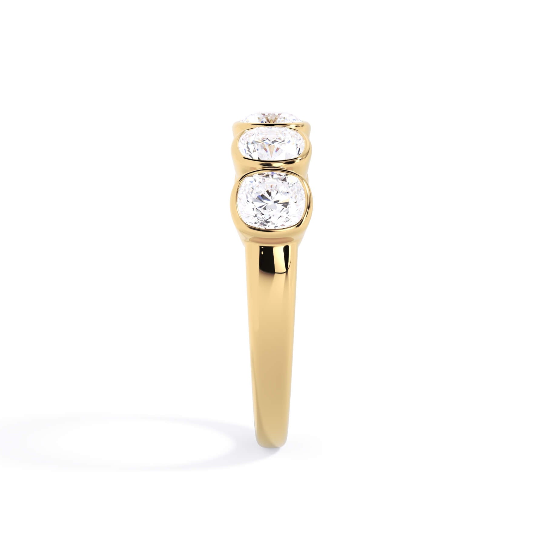 A picture of a five stone diamond wedding ring with cushion shape diamonds that are bezel set in yellow gold on a white background with a side profile view.