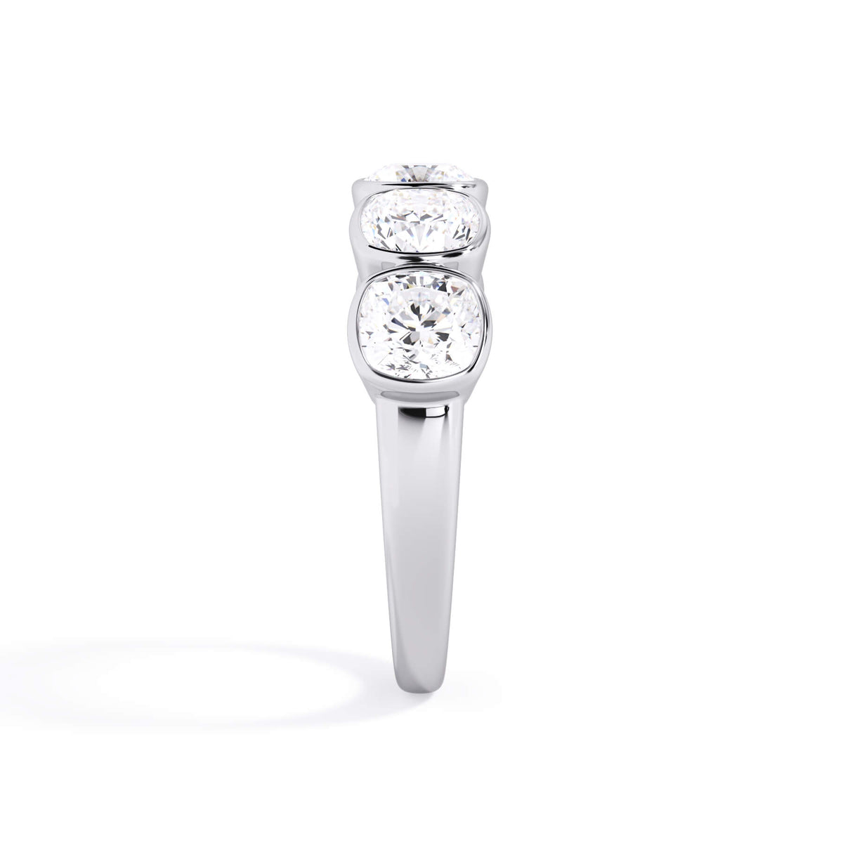 A picture of a five stone diamond wedding ring with cushion shape diamonds that are bezel set in white gold or platinum on a white background with a side profile view.