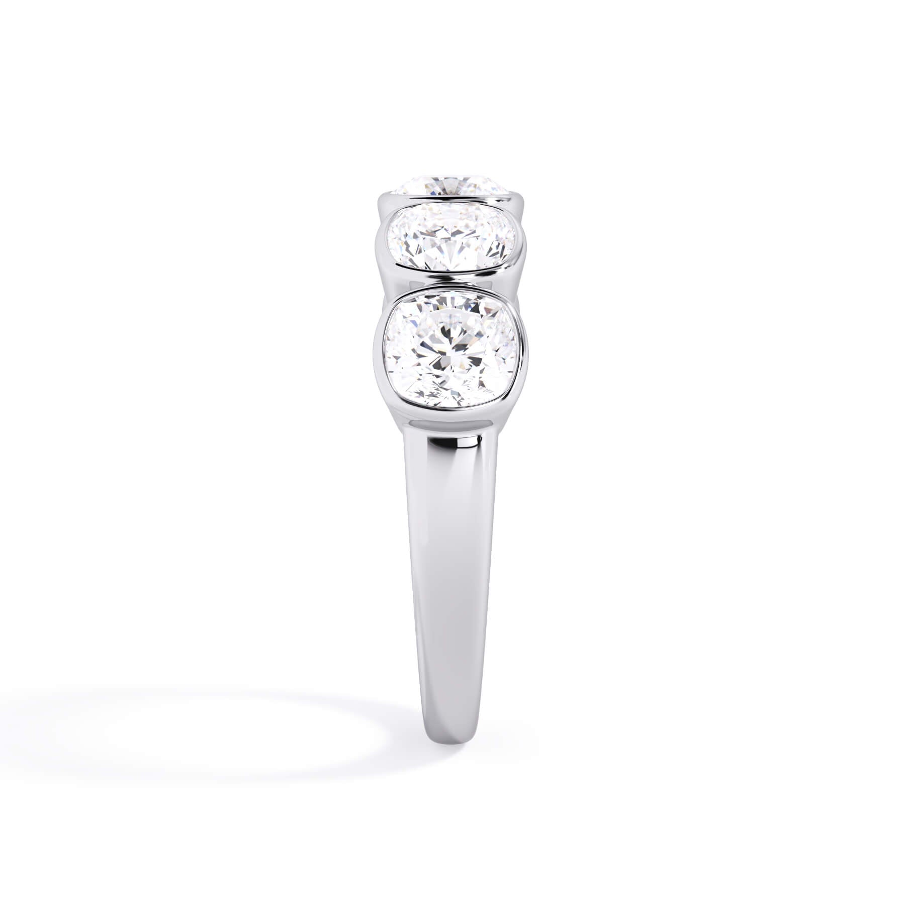 A picture of a five stone diamond wedding ring with cushion shape diamonds that are bezel set in white gold or platinum on a white background with a side profile view.