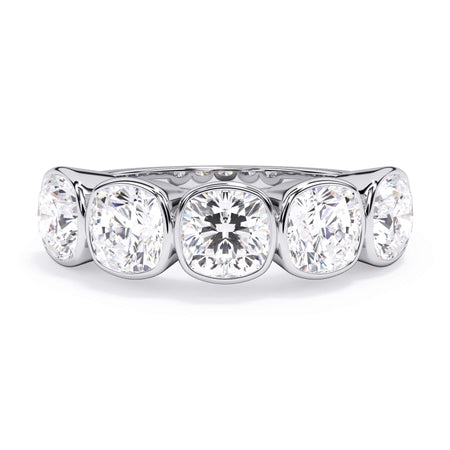 A picture of a five stone diamond wedding ring with cushion shape diamonds that are bezel set in white gold or platinum on a white background with the ring facing forward, lying down.