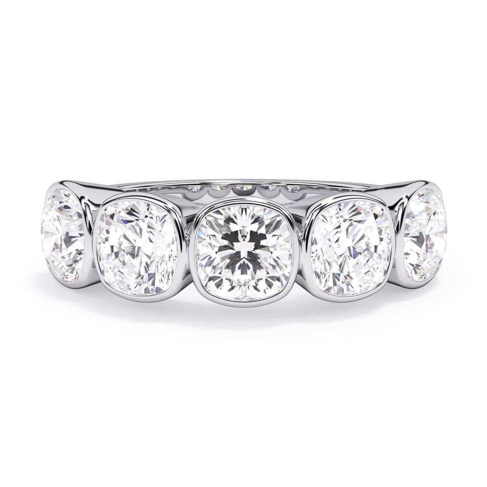 A picture of a five stone diamond wedding ring with cushion shape diamonds that are bezel set in white gold or platinum on a white background with the ring facing forward, lying down.