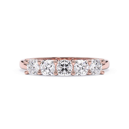 A picture of a five stone diamond wedding ring with cushion shape diamonds that are shared prong set in rose gold on a white background with the ring facing forward, lying down.