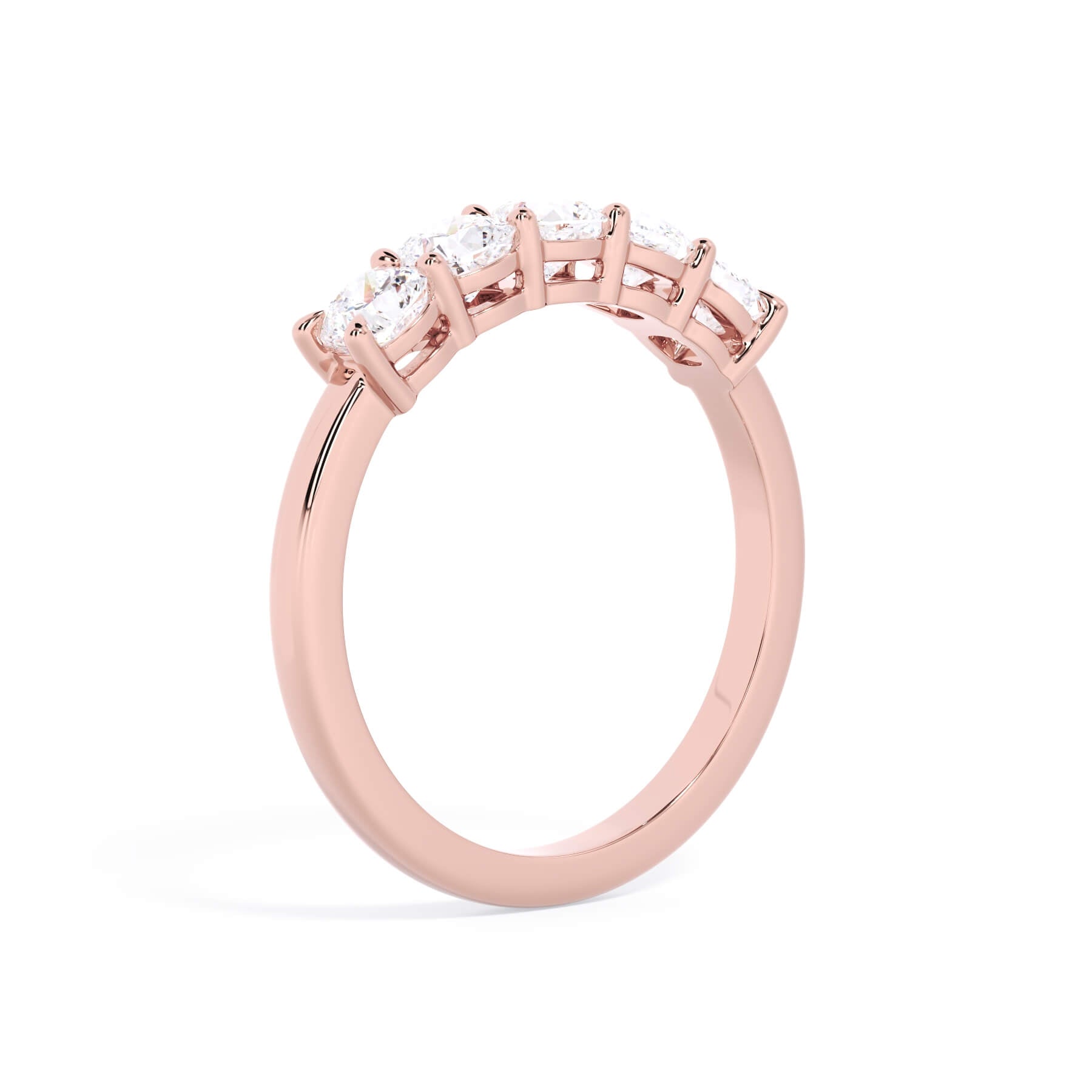 A picture of a five stone diamond wedding ring with cushion shape diamonds that are shared prong set in rose gold on a white background with a slightly angled, through the finger view.