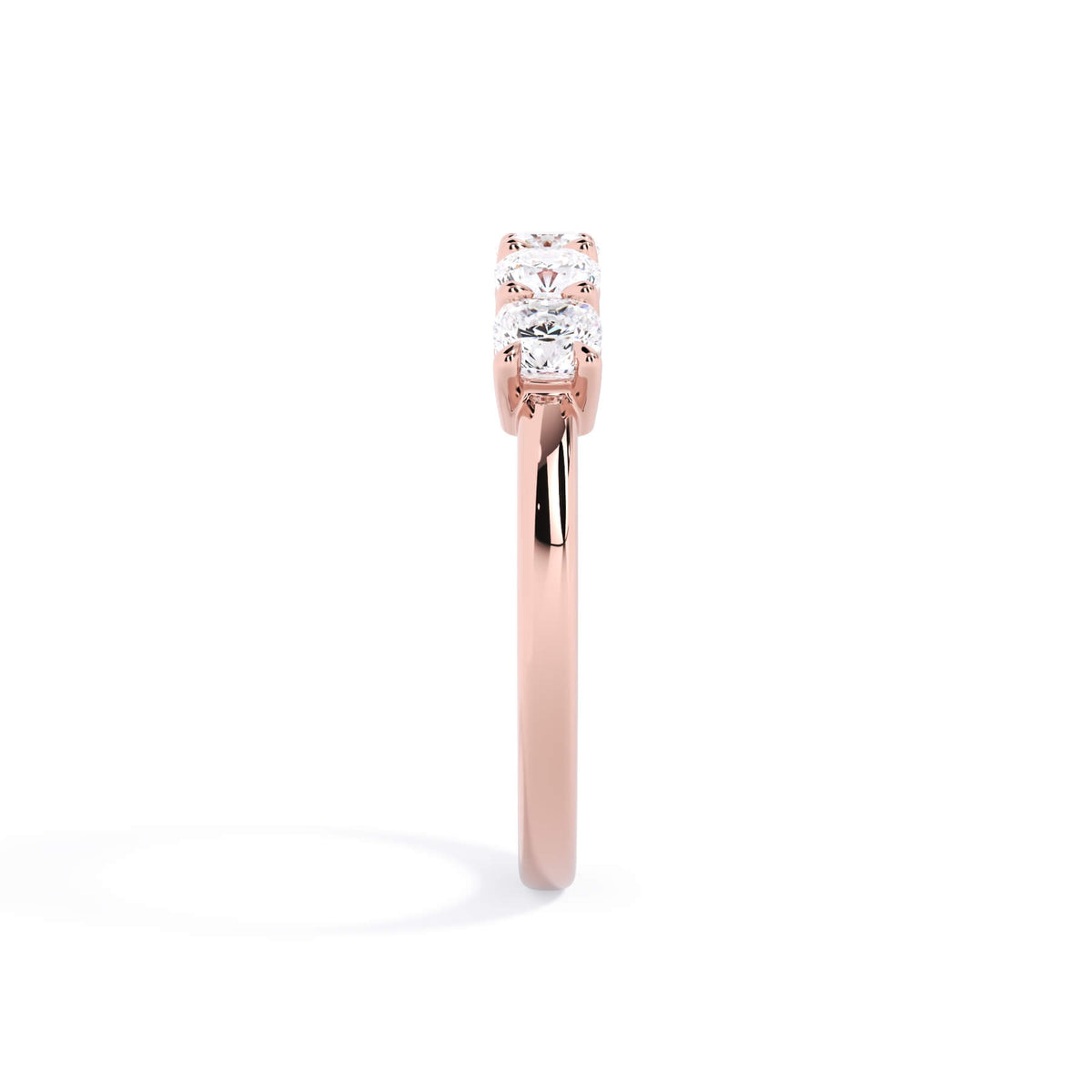 A picture of a five stone diamond wedding ring with cushion shape diamonds that are shared prong set in rose gold on a white background with a side profile view.