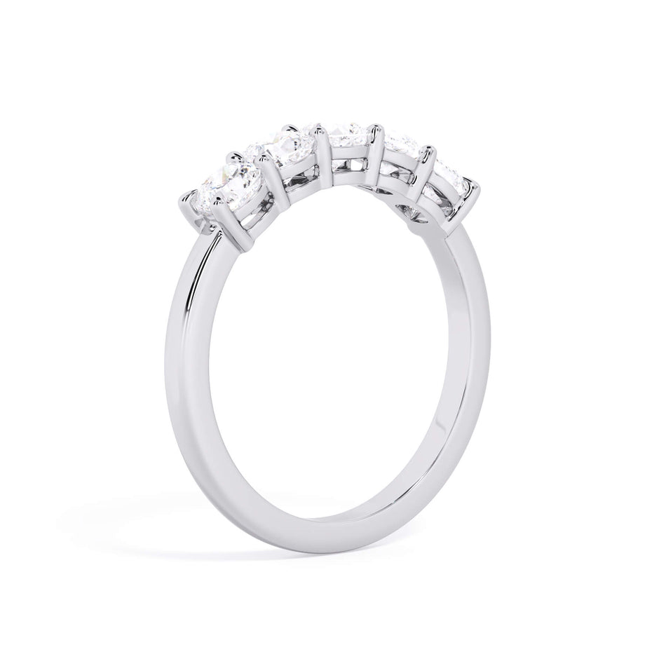 A picture of a five stone diamond wedding ring with cushion shape diamonds that are shared prong set in white gold or platinum on a white background with a slightly angled, through the finger view.