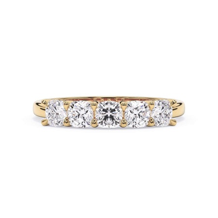 A picture of a five stone diamond wedding ring with cushion shape diamonds that are shared prong set in yellow gold on a white background with the ring facing forward, lying down.