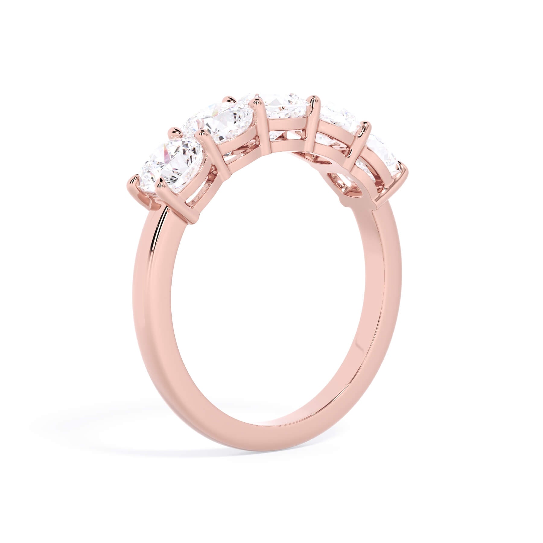 A picture of a five stone diamond wedding ring with cushion shape diamonds that are shared prong set in rose gold on a white background with a slightly angled, through the finger view.