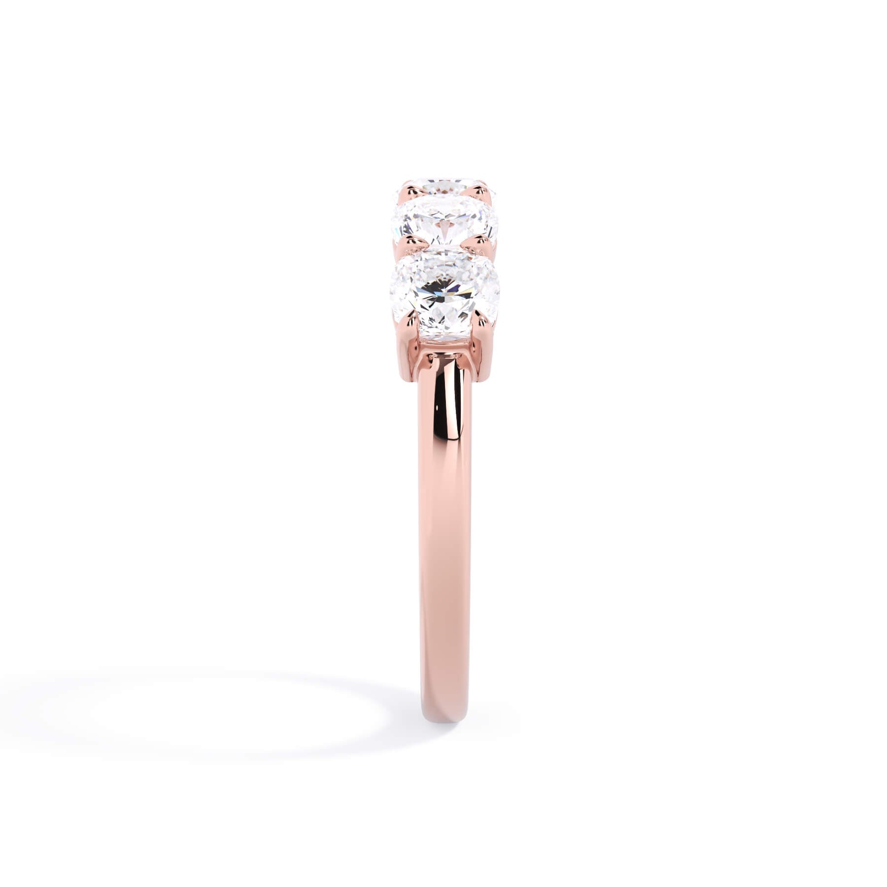 A picture of a five stone diamond wedding ring with cushion shape diamonds that are shared prong set in rose gold on a white background with a side profile view.