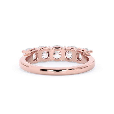 A picture of a five stone diamond wedding ring with cushion shape diamonds that are shared prong set in rose gold on a white background with a view of the underside of the ring.