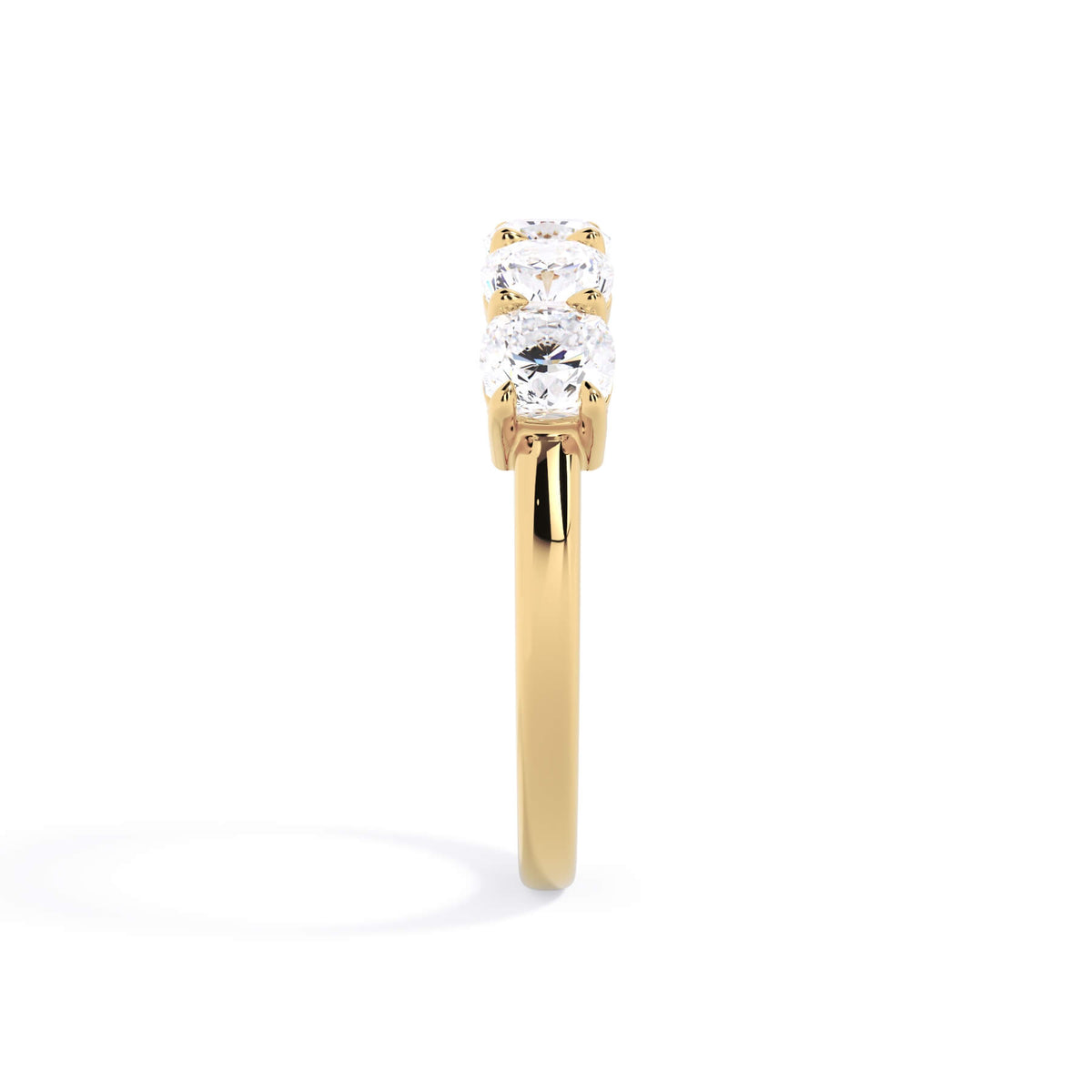 A picture of a five stone diamond wedding ring with cushion shape diamonds that are shared prong set in yellow gold on a white background with a side profile view.