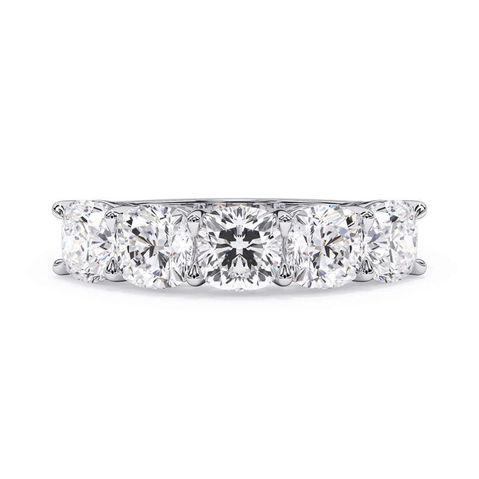A picture of a five stone diamond wedding ring with cushion shape diamonds that are shared prong set in white gold or platinum on a white background with the ring facing forward, lying down.