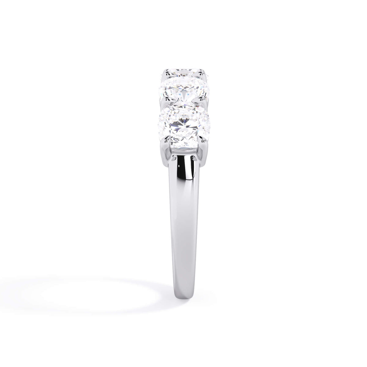 A picture of a five stone diamond wedding ring with cushion shape diamonds that are shared prong set in white gold or platinum on a white background with a side profile view.