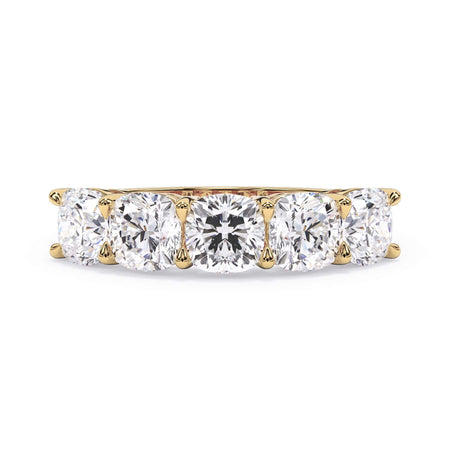 A picture of a five stone diamond wedding ring with cushion shape diamonds that are shared prong set in yellow gold on a white background with the ring facing forward, lying down.