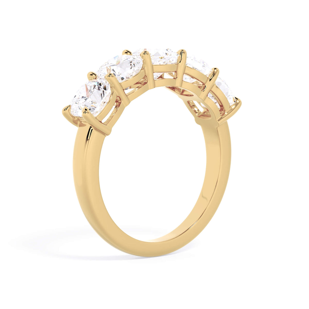 A picture of a five stone diamond wedding ring with cushion shape diamonds that are shared prong set in yellow gold on a white background with a slightly angled, through the finger view.