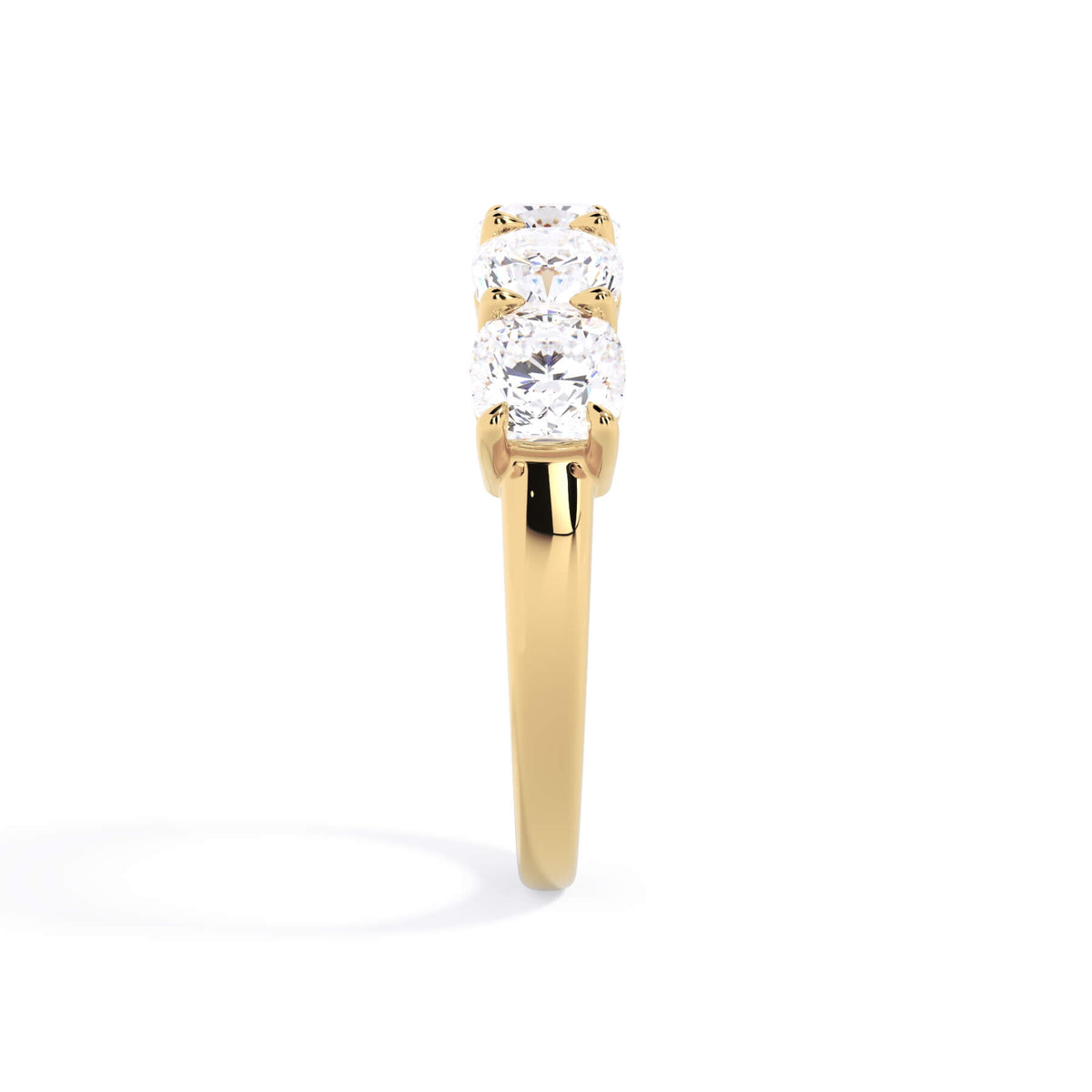 A picture of a five stone diamond wedding ring with cushion shape diamonds that are shared prong set in yellow gold on a white background with a side profile view.