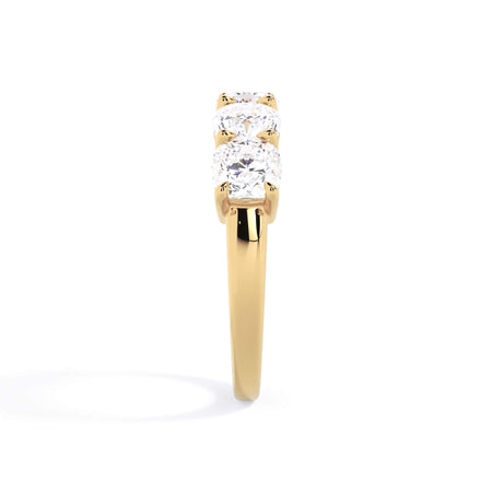 A picture of a five stone diamond wedding ring with cushion shape diamonds that are shared prong set in yellow gold on a white background with a side profile view.