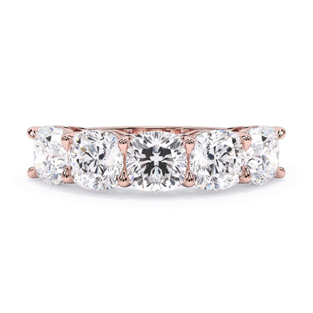 A picture of a five stone diamond wedding ring with cushion shape diamonds that are shared prong set in rose gold on a white background with the ring facing forward, lying down.