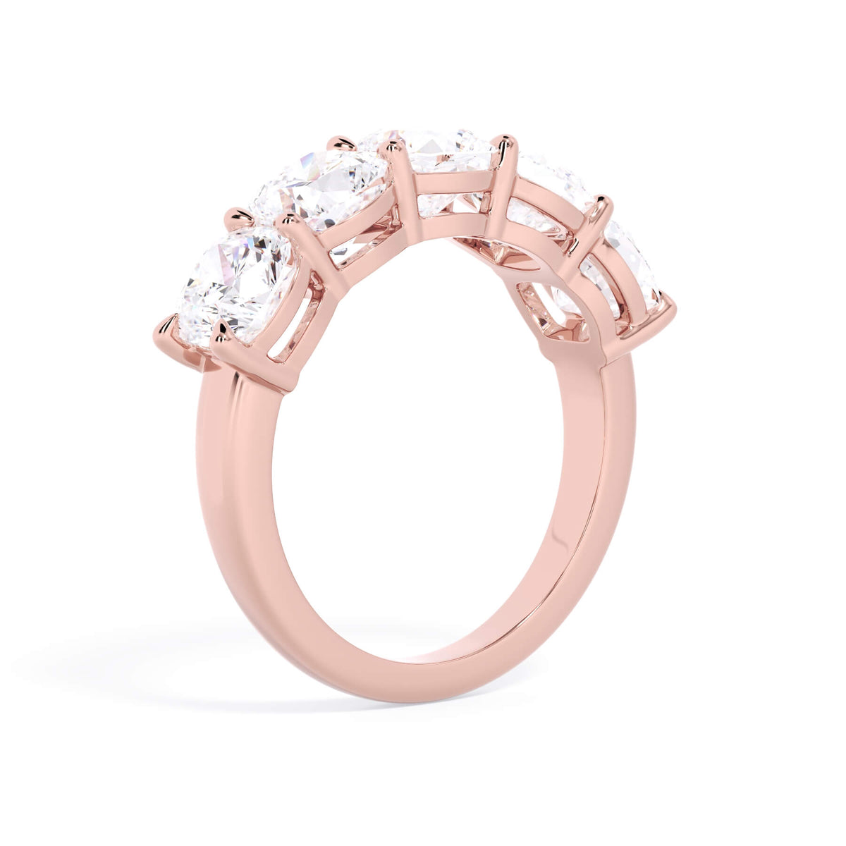 A picture of a five stone diamond wedding ring with cushion shape diamonds that are shared prong set in rose gold on a white background with a slightly angled, through the finger view.